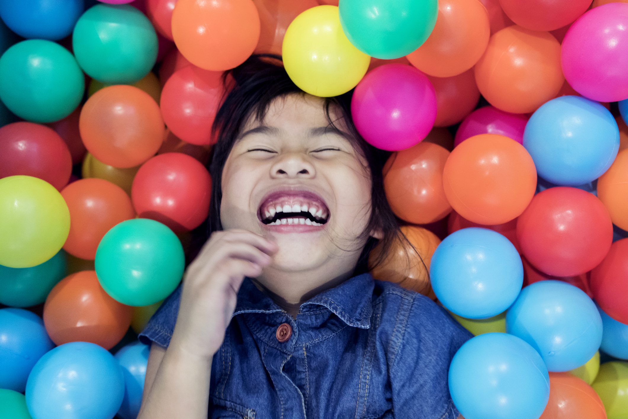 A Joyful Little Girl Giggling While Immersed in a Colorful Ball